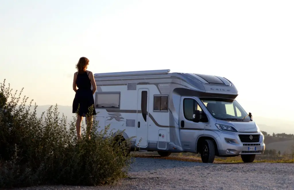 Viajante ao lado de uma autocaravana branca pronta para uma nova aventura.
